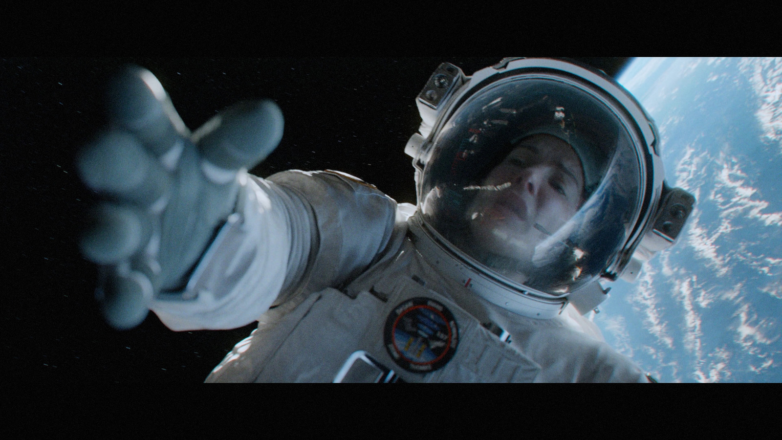 a man in a spacesuit pointing at the earth