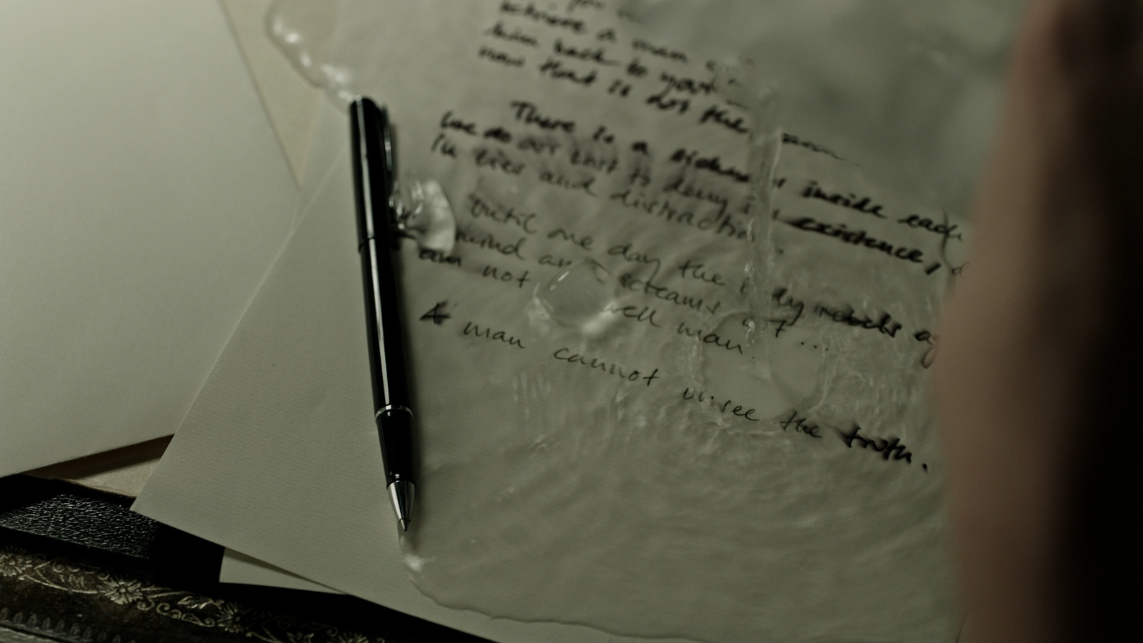 a person writing on a piece of paper with a pen