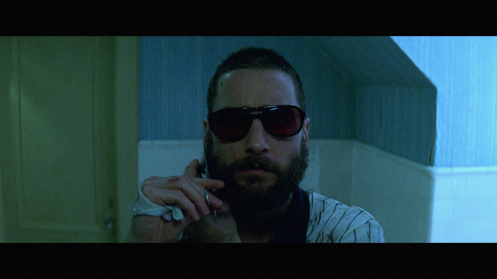 a man with a beard wearing sunglasses and holding a cell phone