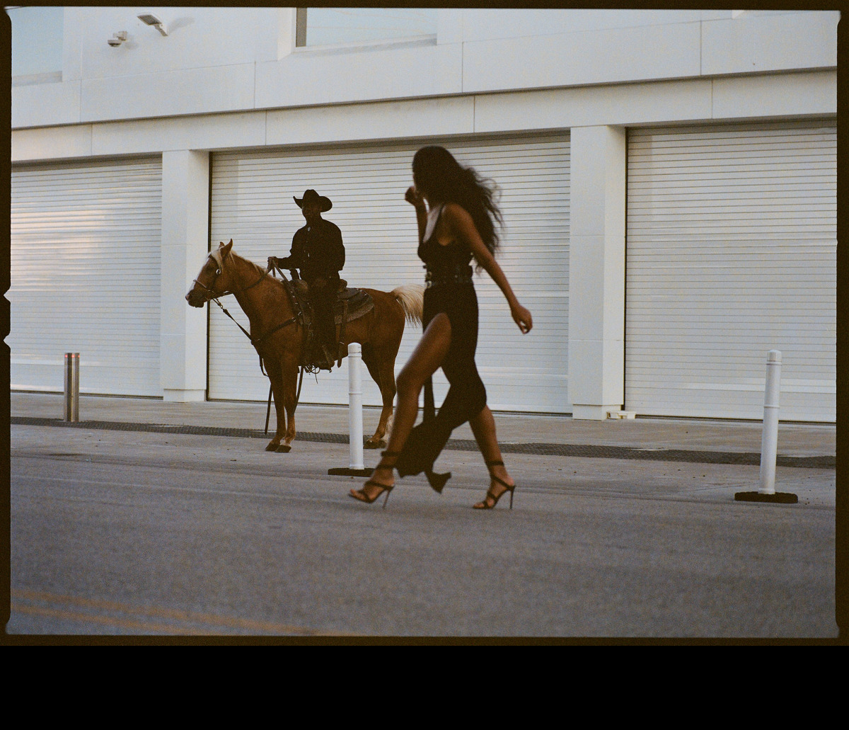 a woman walking down a street next to a horse