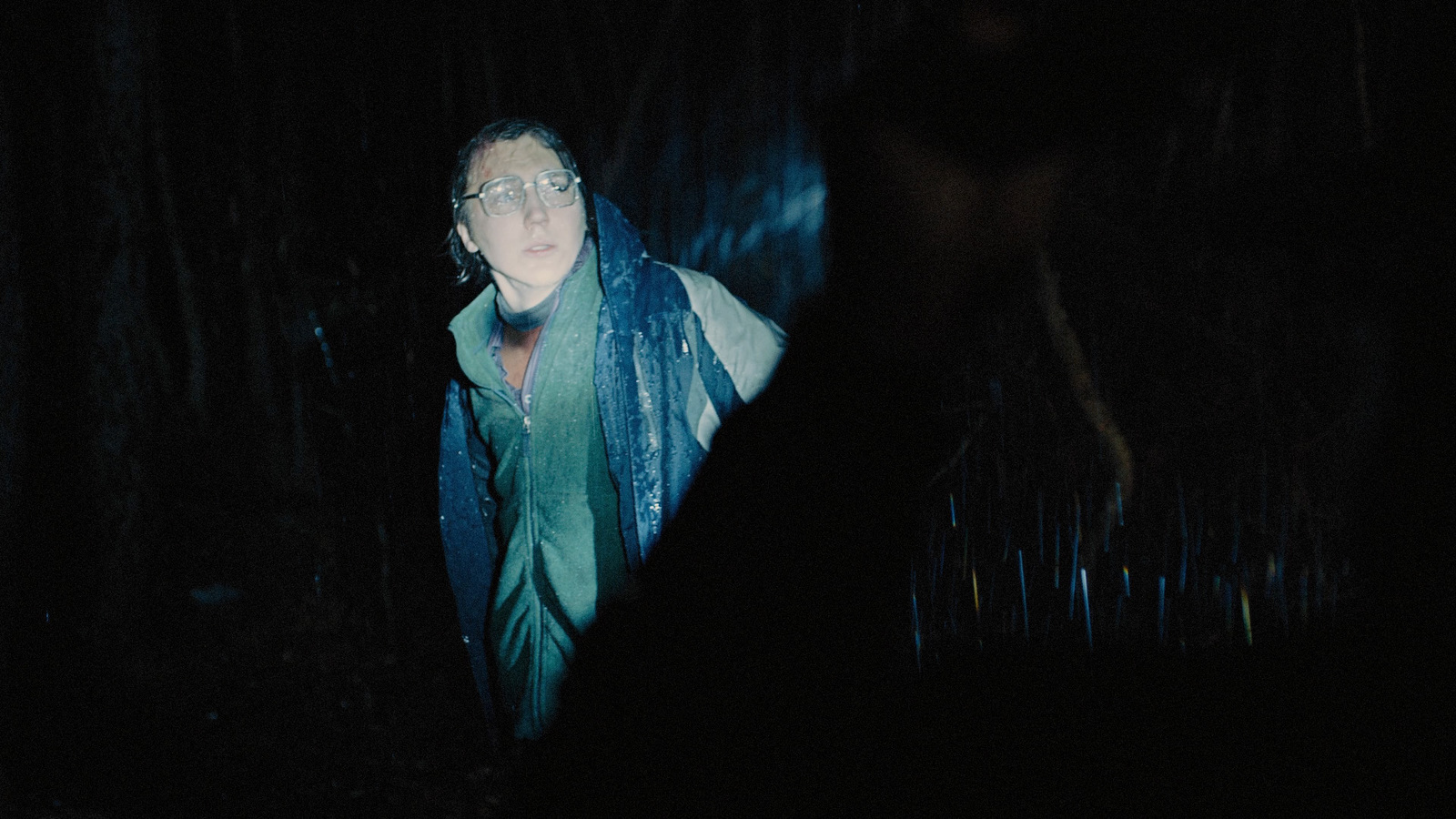 a man standing in the dark with a scarf around his neck