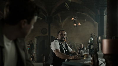 a man sitting at a bar with a glass of beer