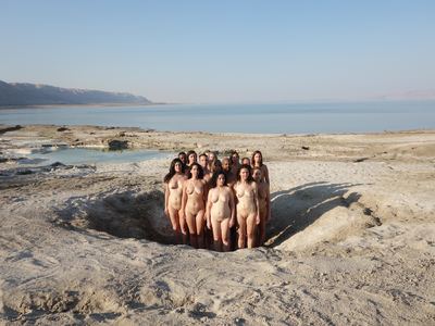 a group of naked women standing in the sand