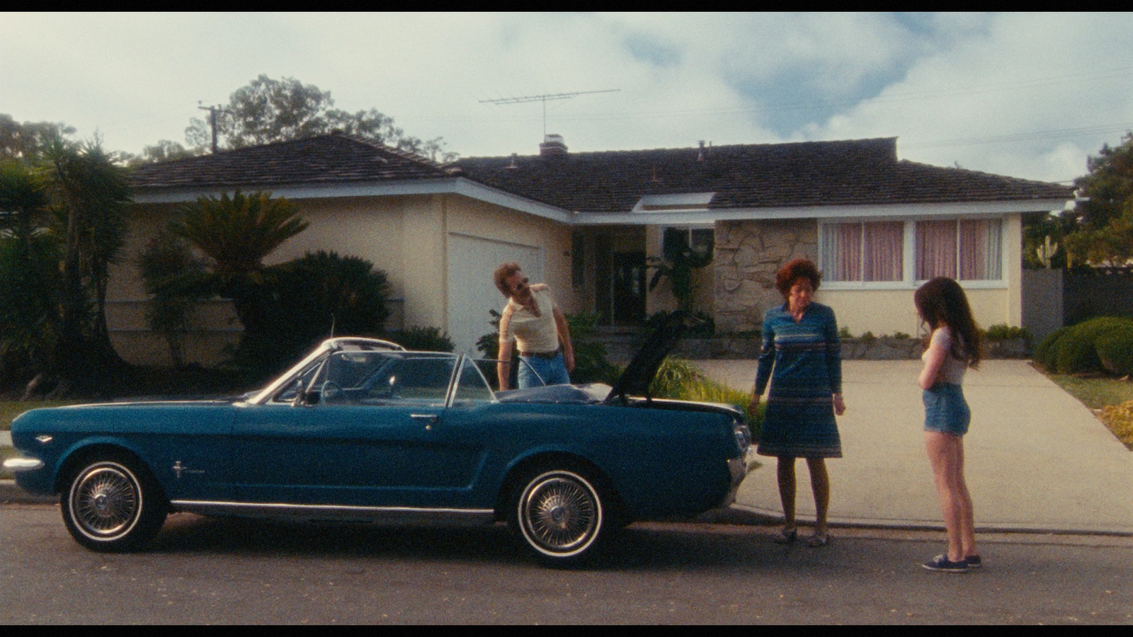 a group of people standing in front of a blue car