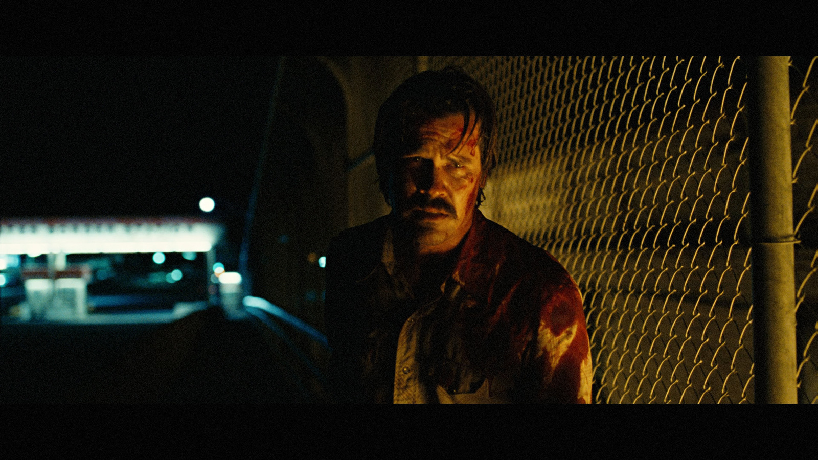 a man standing next to a fence at night