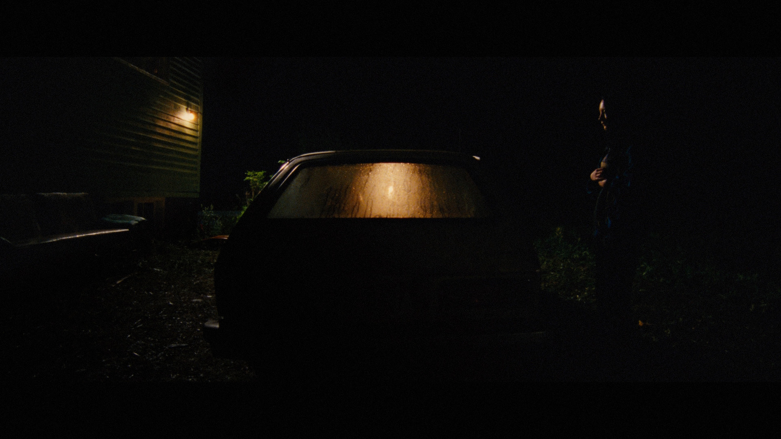 a man standing next to a car in the dark