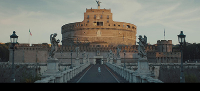 a person walking across a bridge with a castle in the background