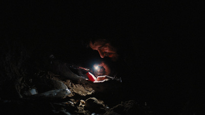 a man holding a flashlight in a dark cave