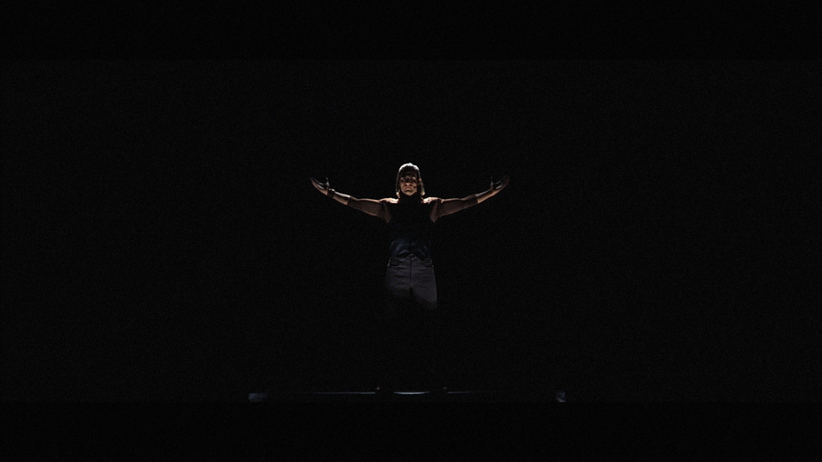 a man standing in the dark with his arms outstretched