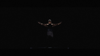 a man standing in the dark with his arms outstretched