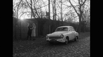 a black and white photo of a man and a woman standing next to a car