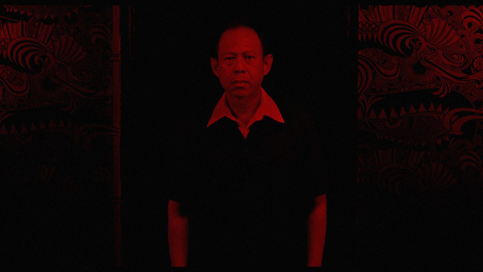 a man standing in a dark room with a red light