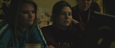 three women looking at a computer screen in a dark room