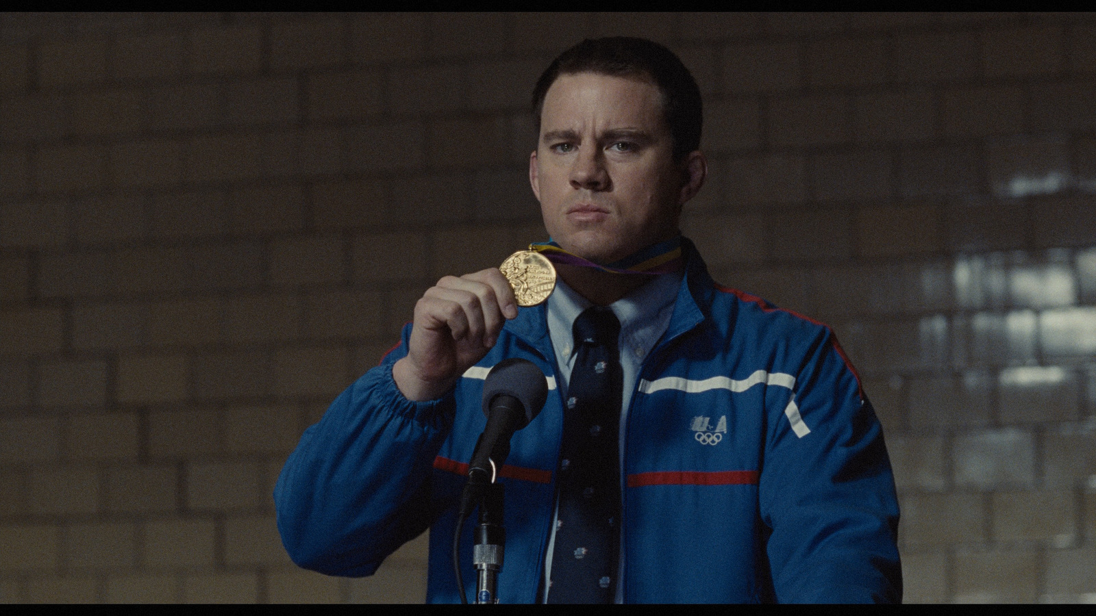 a man in a blue jacket holding a gold medal