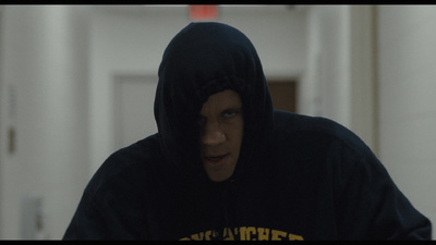 a man wearing a hoodie in a hallway