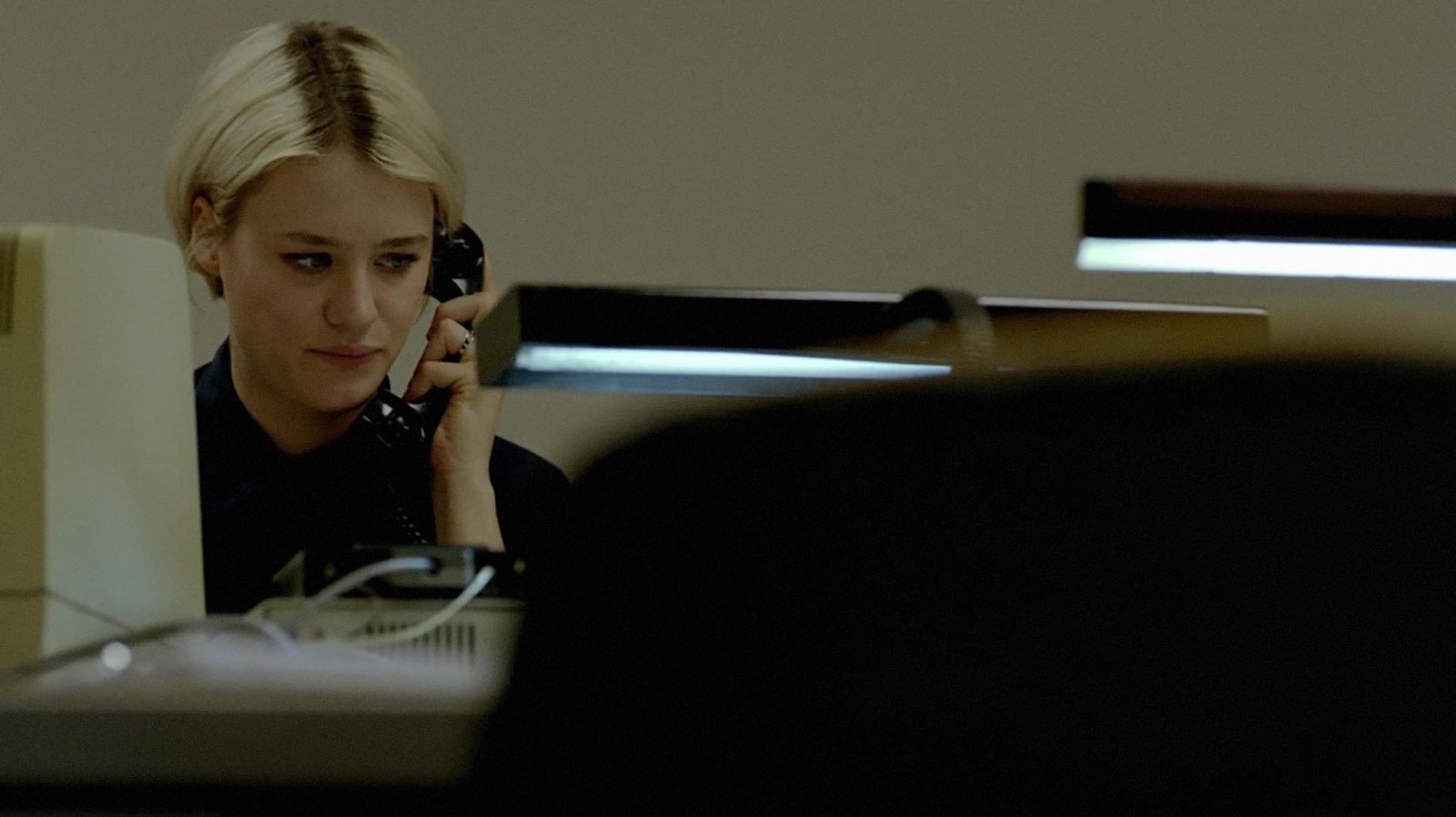 a woman sitting at a desk talking on a phone