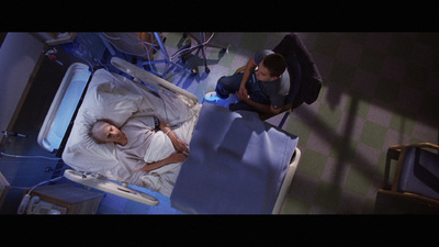 a man laying in a hospital bed next to another man