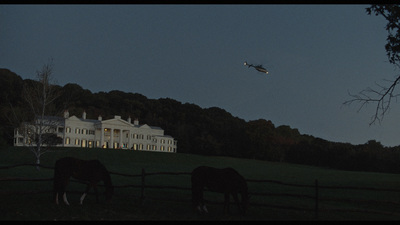 horses graze in front of a large white house