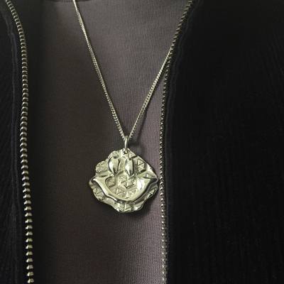 a person wearing a necklace with a flower on it