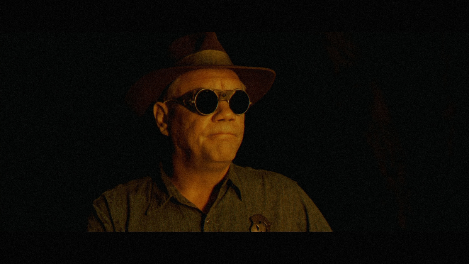 a man wearing sunglasses and a hat in the dark