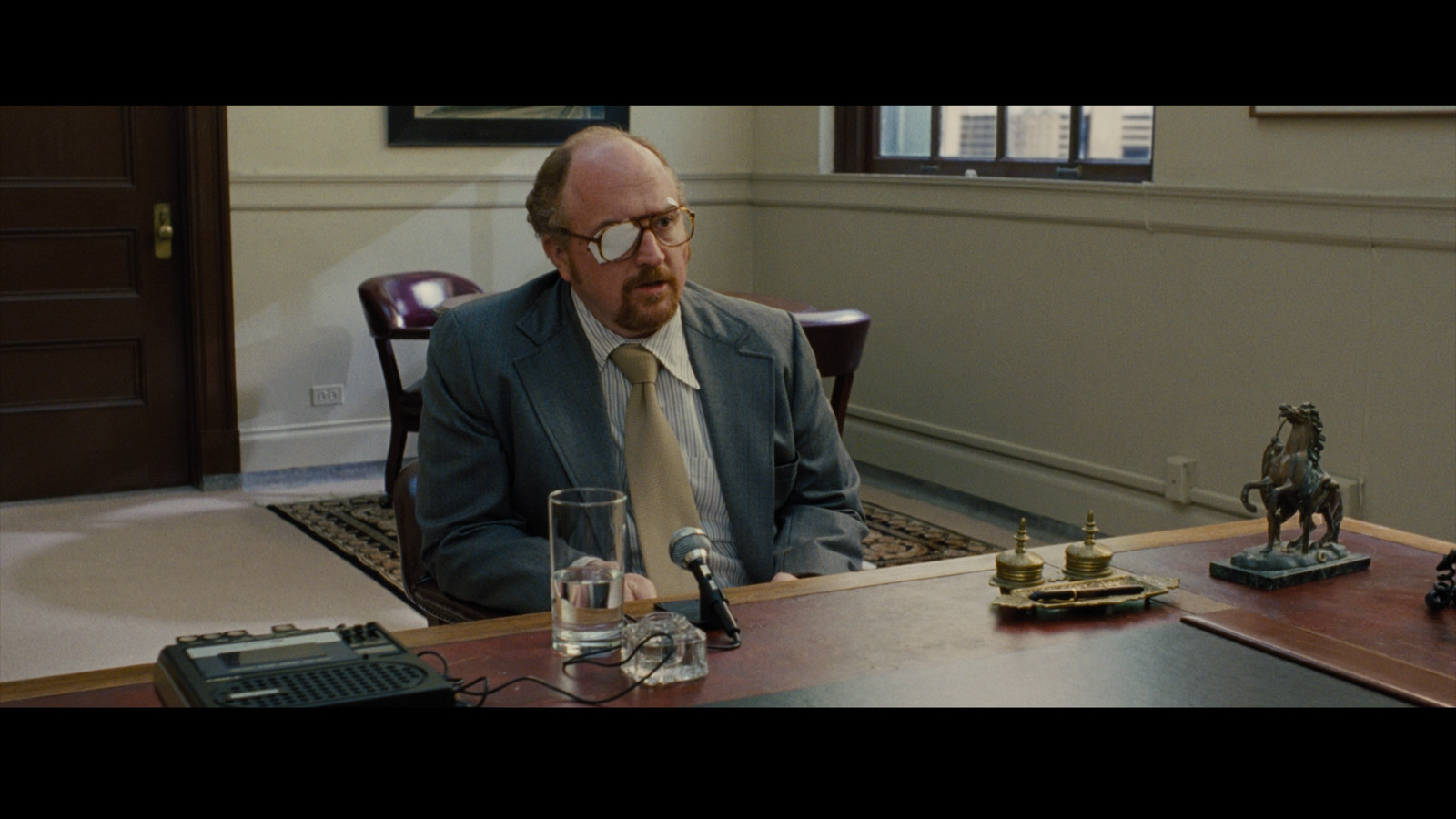 a man in a suit and tie sitting at a desk