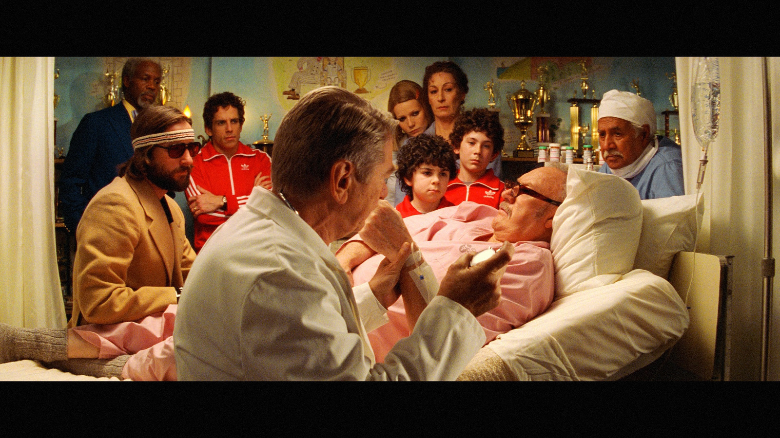 a group of people sitting around a man in a hospital bed