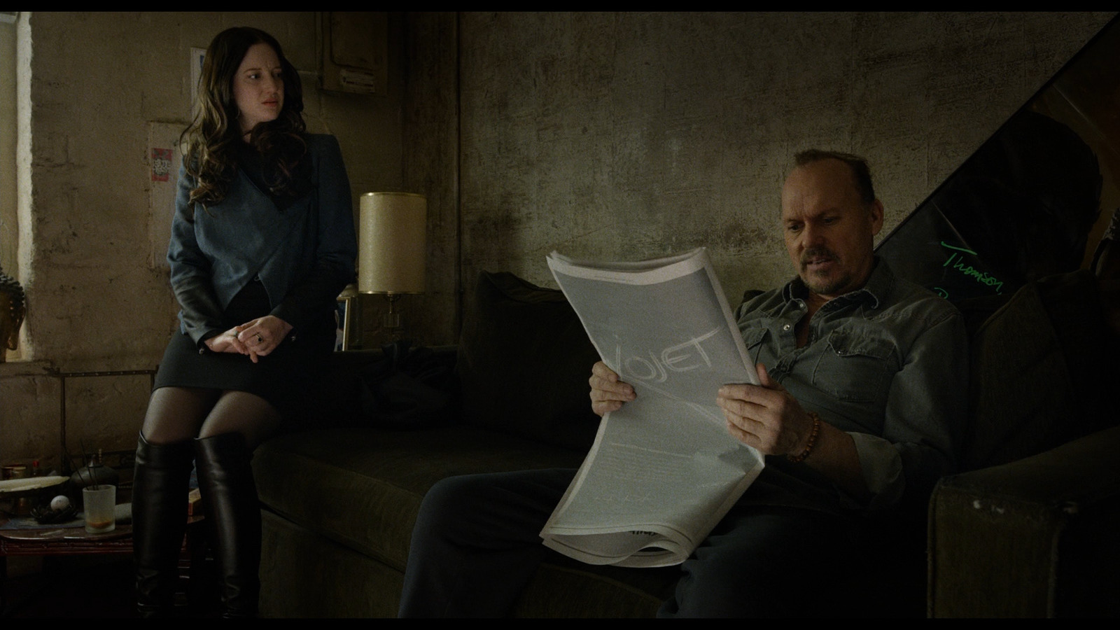 a man and a woman sitting on a couch looking at a piece of paper