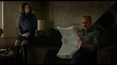 a man and a woman sitting on a couch looking at a piece of paper