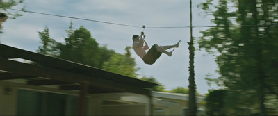 a man hanging from a rope while riding a skateboard