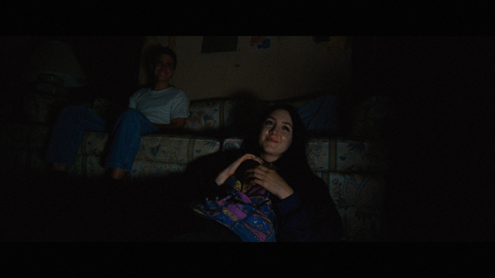 a woman sitting on a couch in a dark room