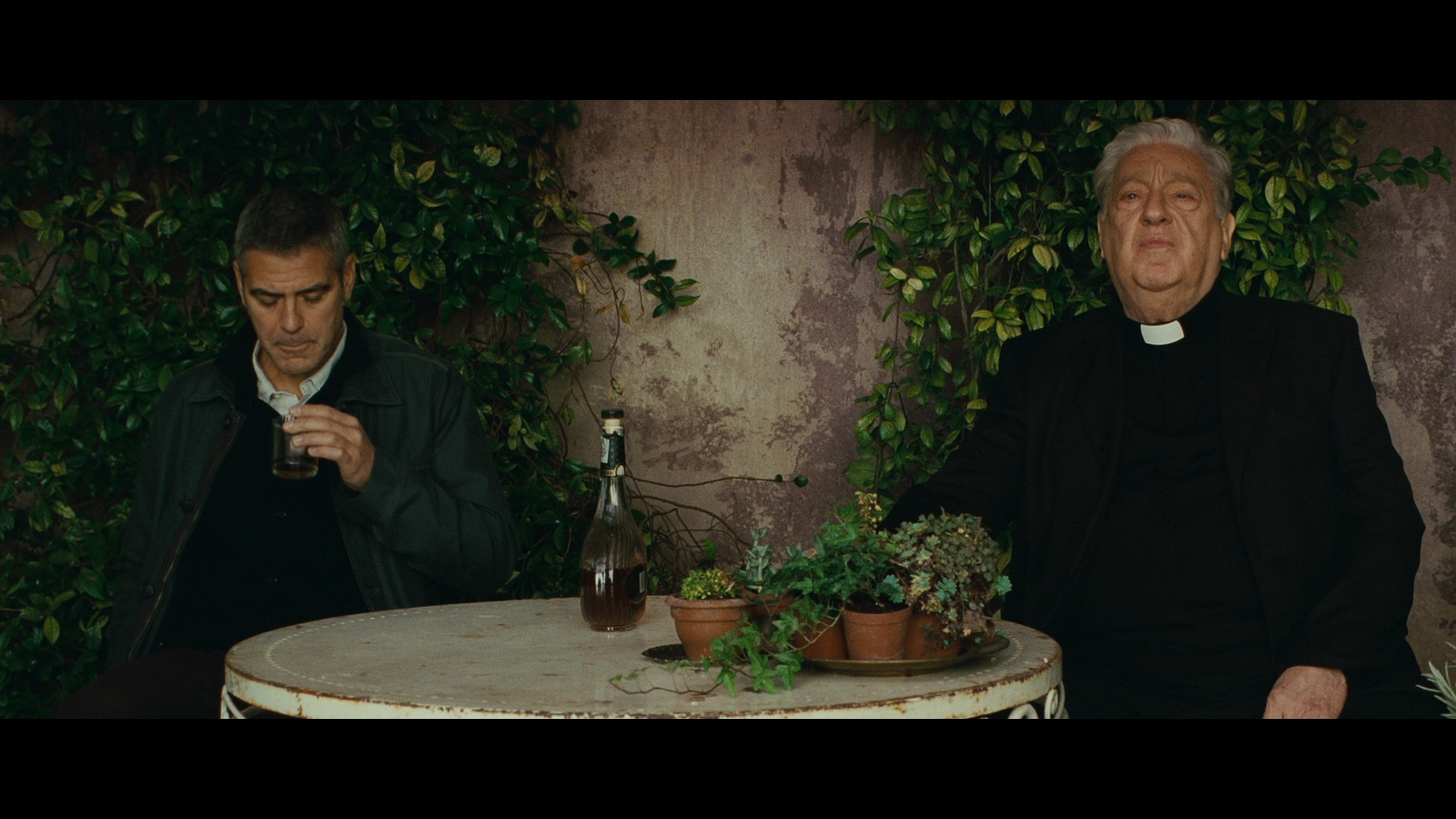 two men sitting at a table with a bottle of wine