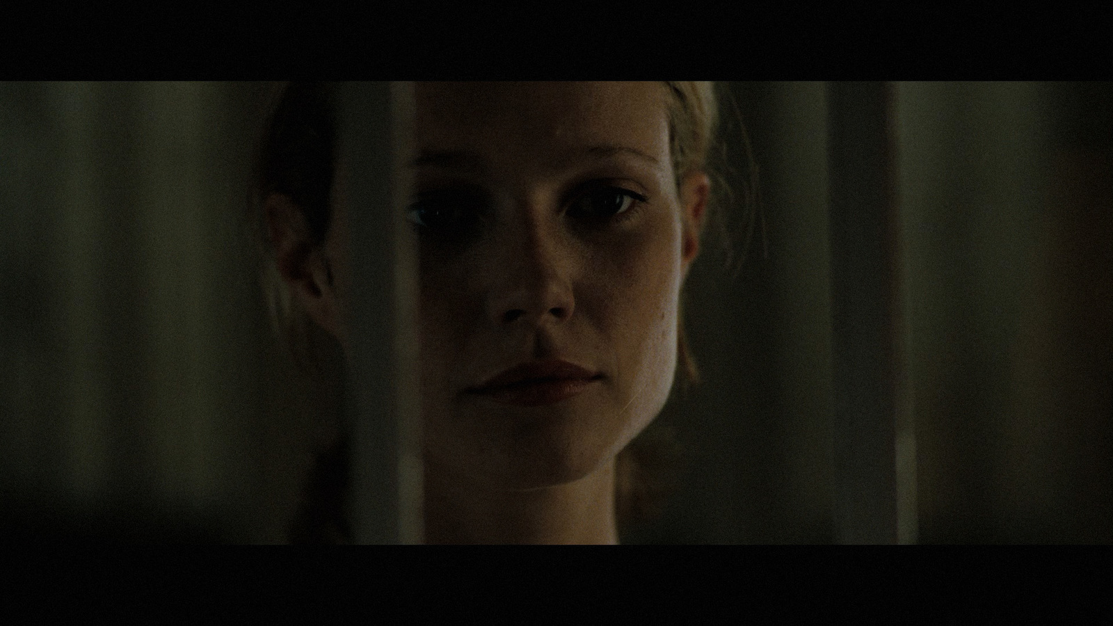 a woman looking through the bars of a window