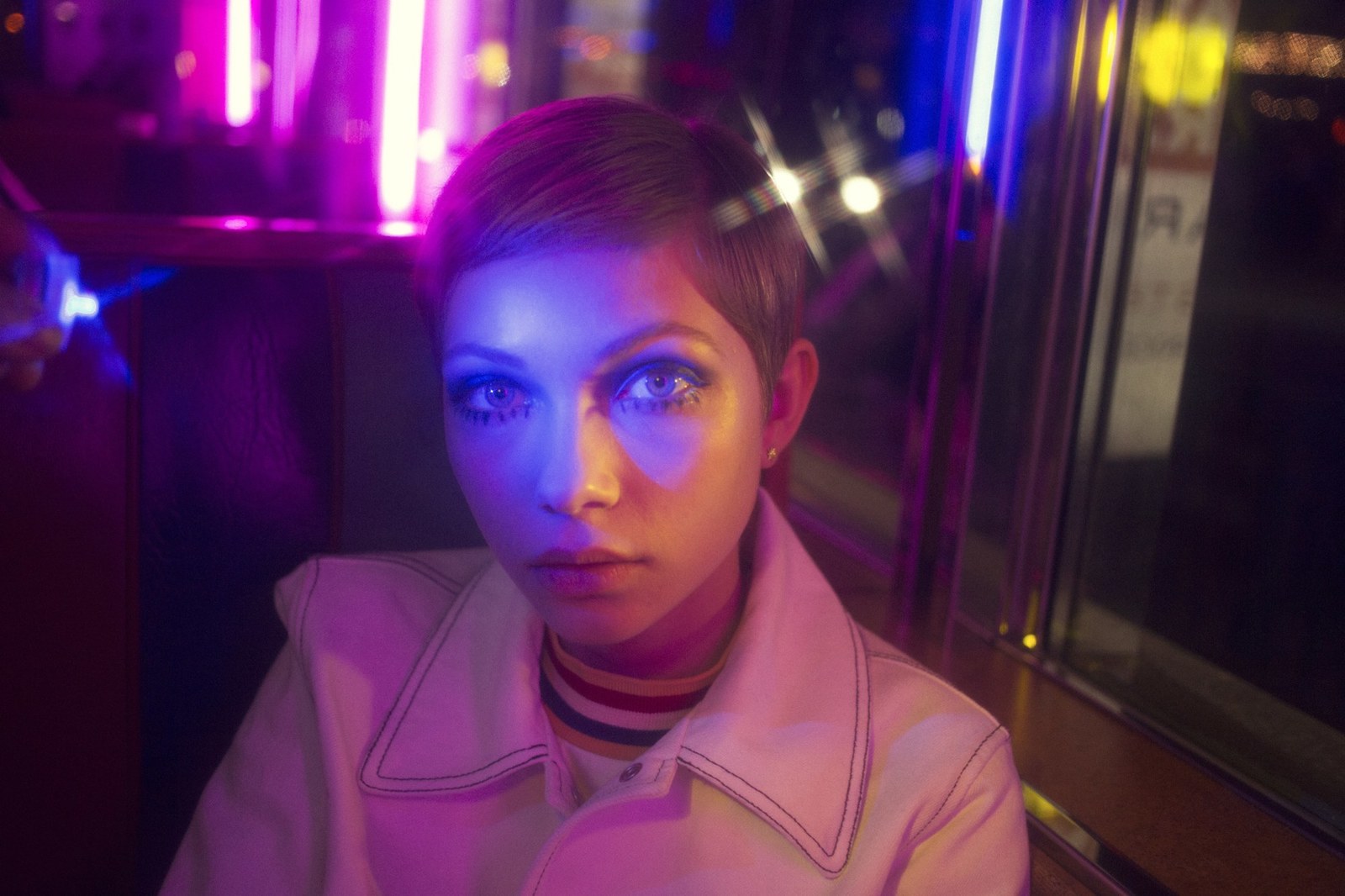 a woman sitting in front of a purple light