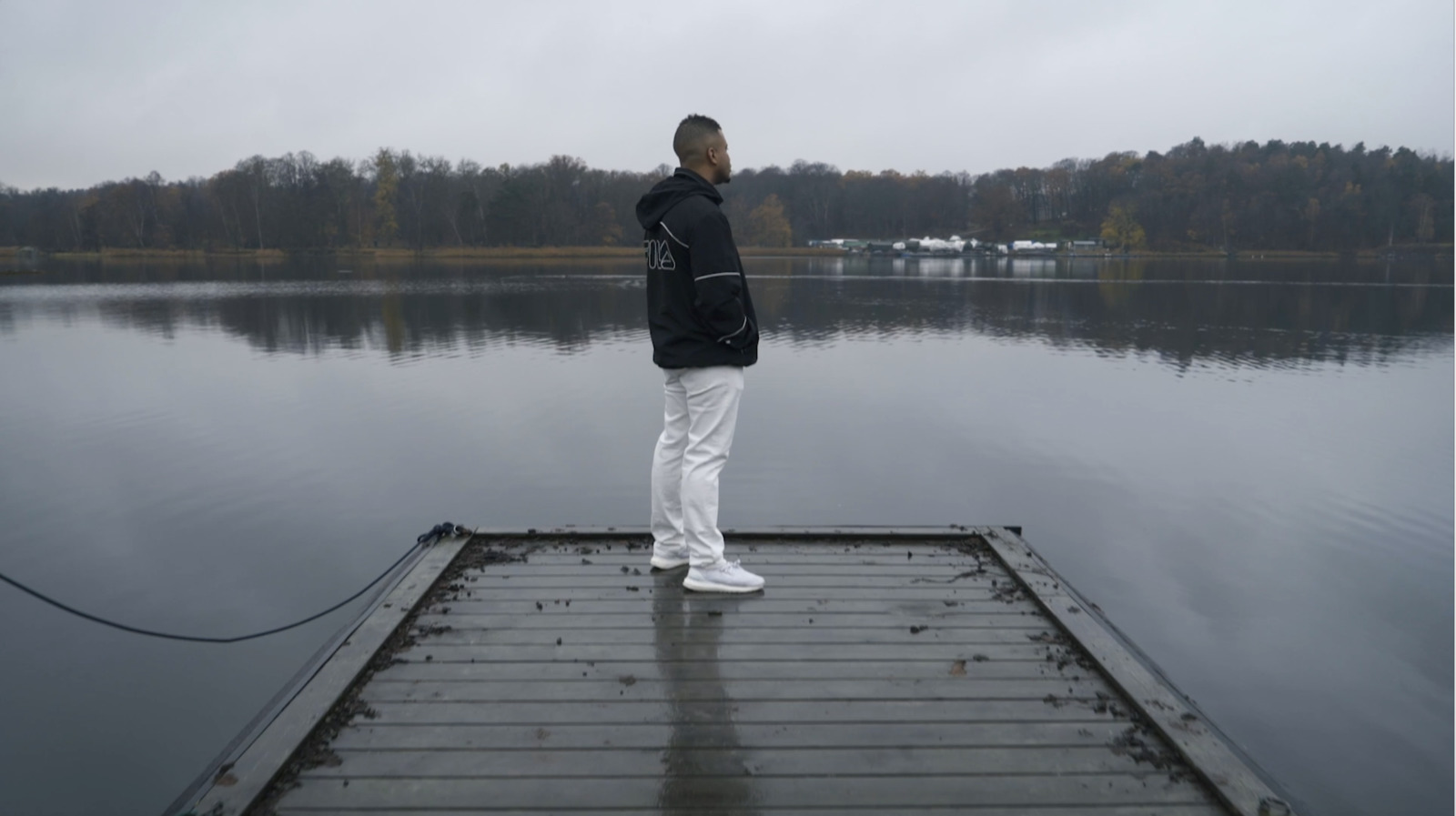 a man standing on a dock next to a body of water