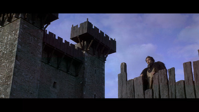 a man sitting on a wooden fence next to a castle