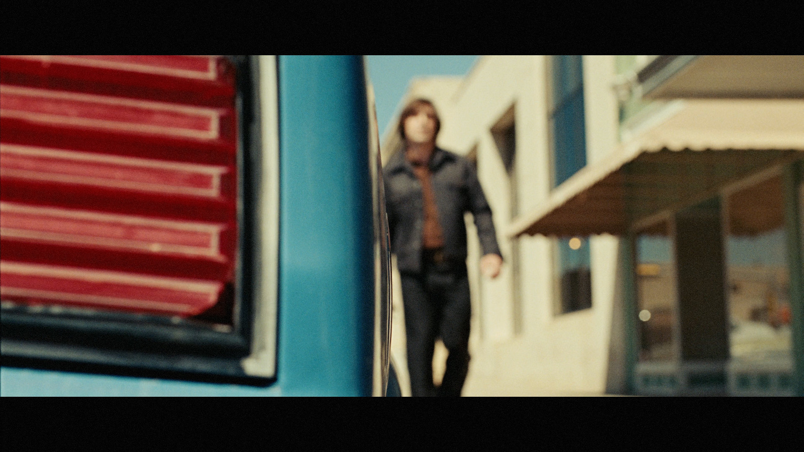 a man walking down a street next to a building