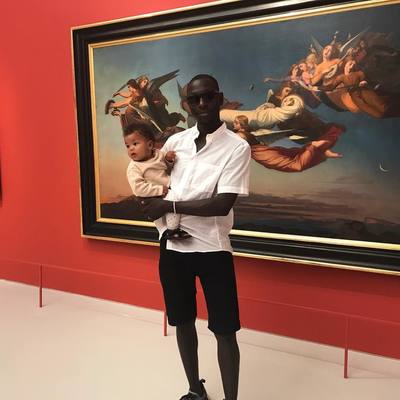 a man holding a baby in front of a painting