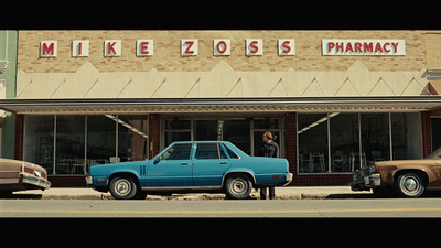 a blue car parked in front of a pharmacy