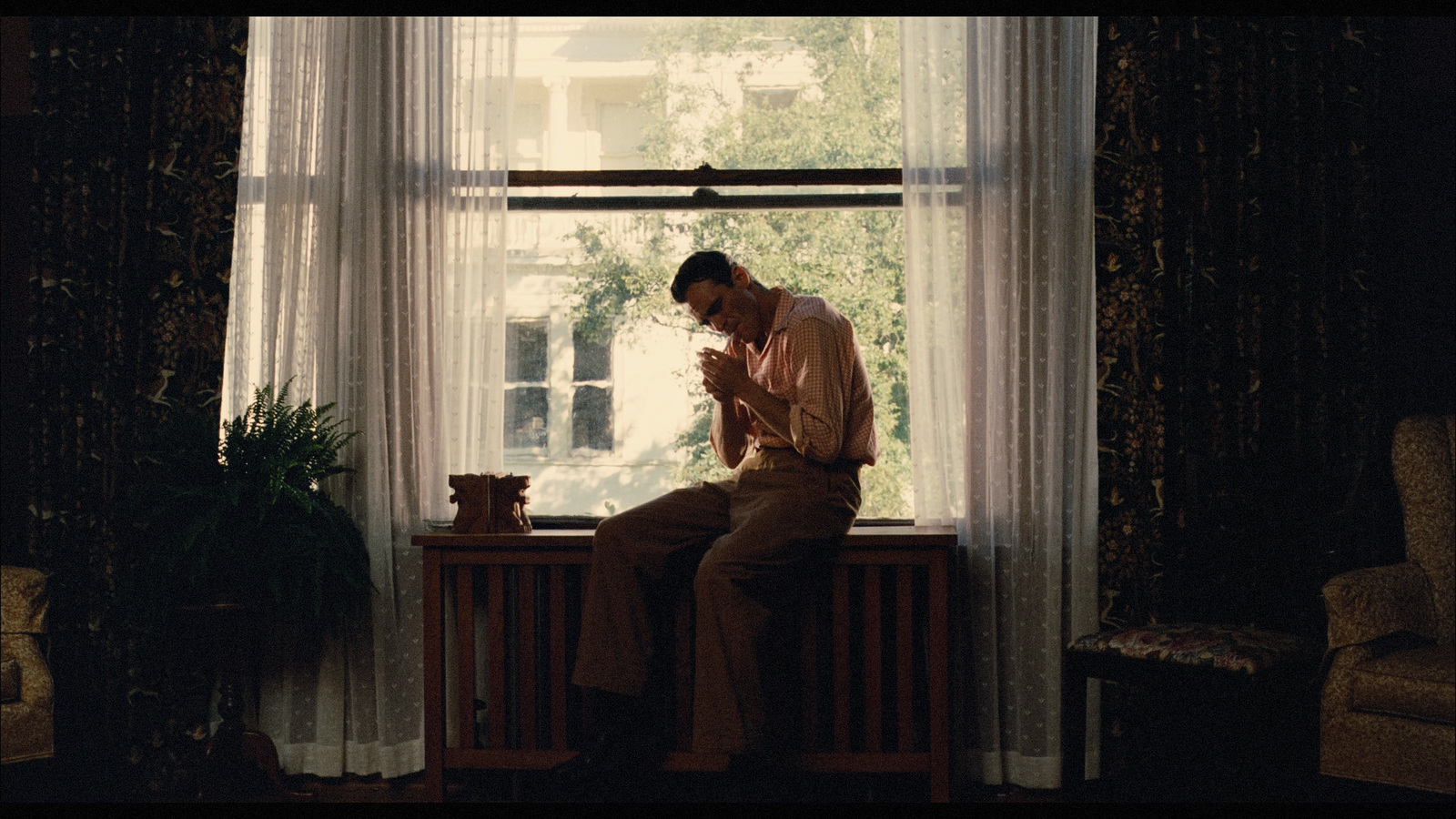 a man sitting on a window sill in front of a window