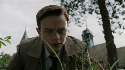 a man in a trench coat looking at the camera