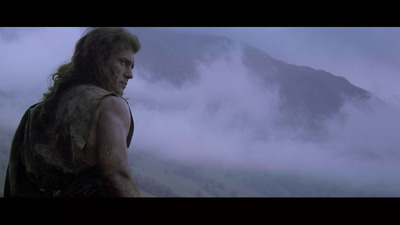 a man with long hair standing in front of a mountain