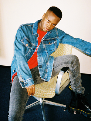 a man sitting in a chair wearing a jean jacket