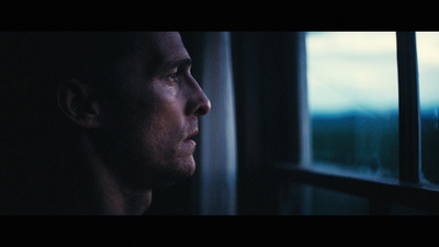 a man looking out of a window in the dark