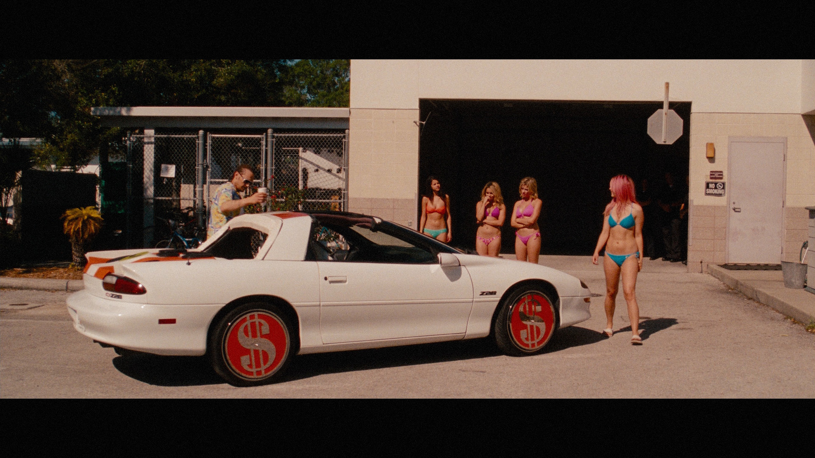 a woman in a bikini standing next to a white sports car