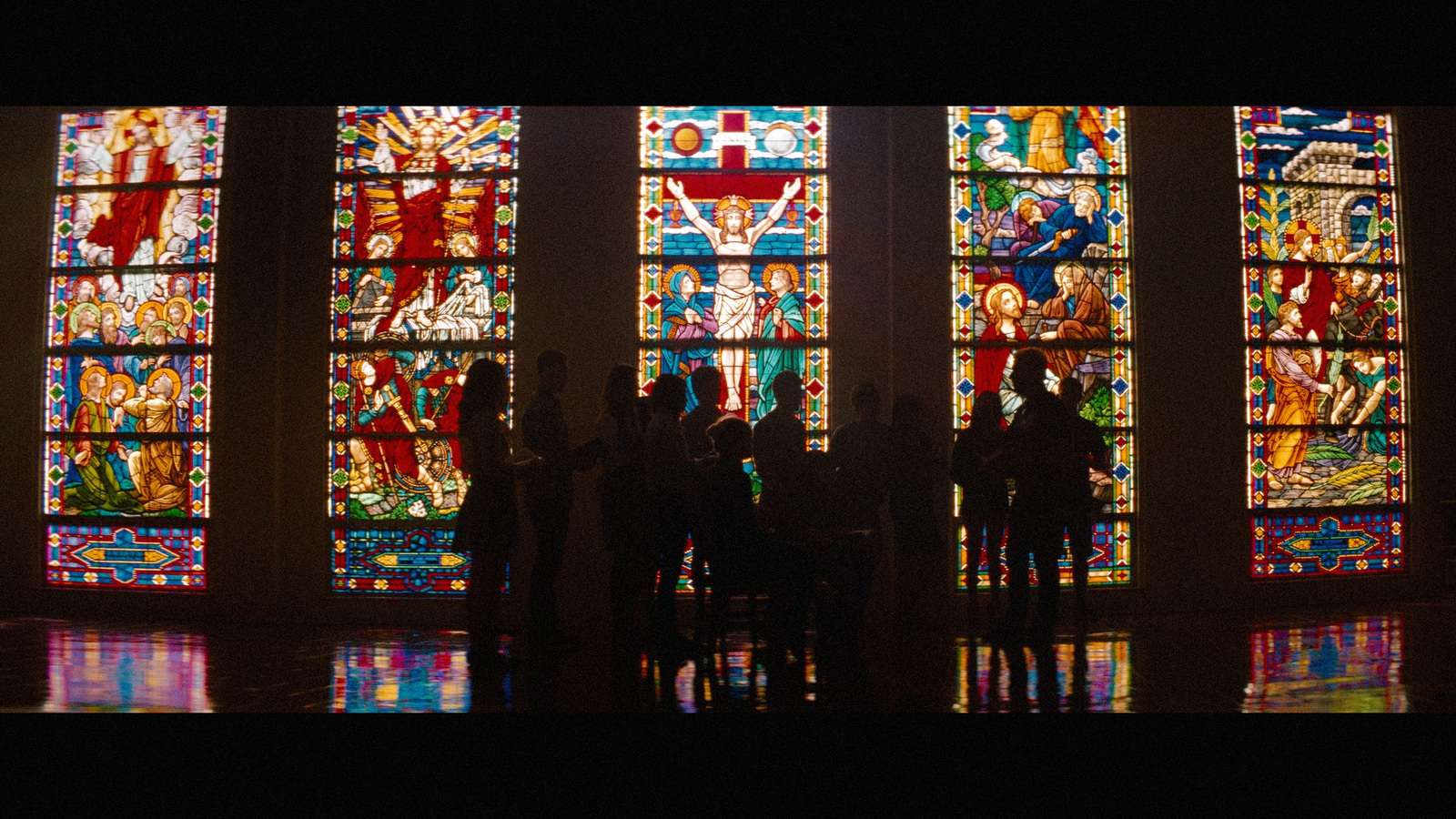 a group of people standing in front of a stained glass window