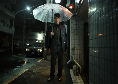 a man standing on a sidewalk holding an umbrella