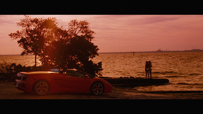 a red sports car parked next to a body of water