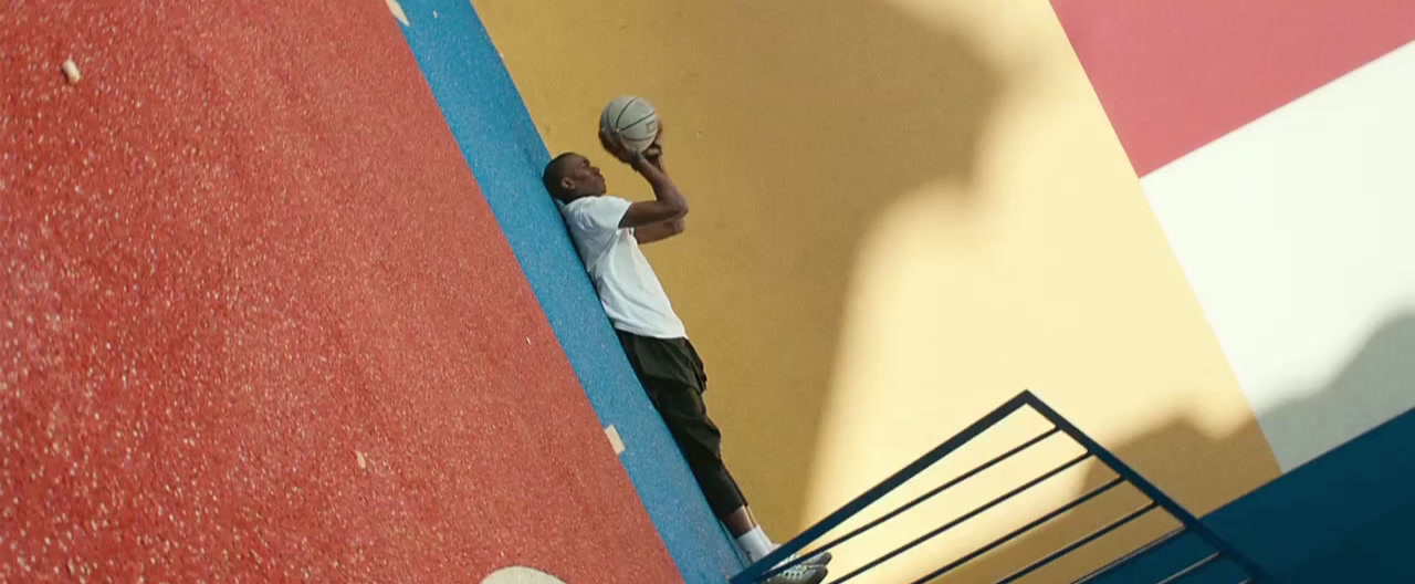 a man holding a ball up against a colorful wall