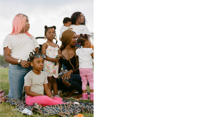 a group of people sitting on top of a grass covered field