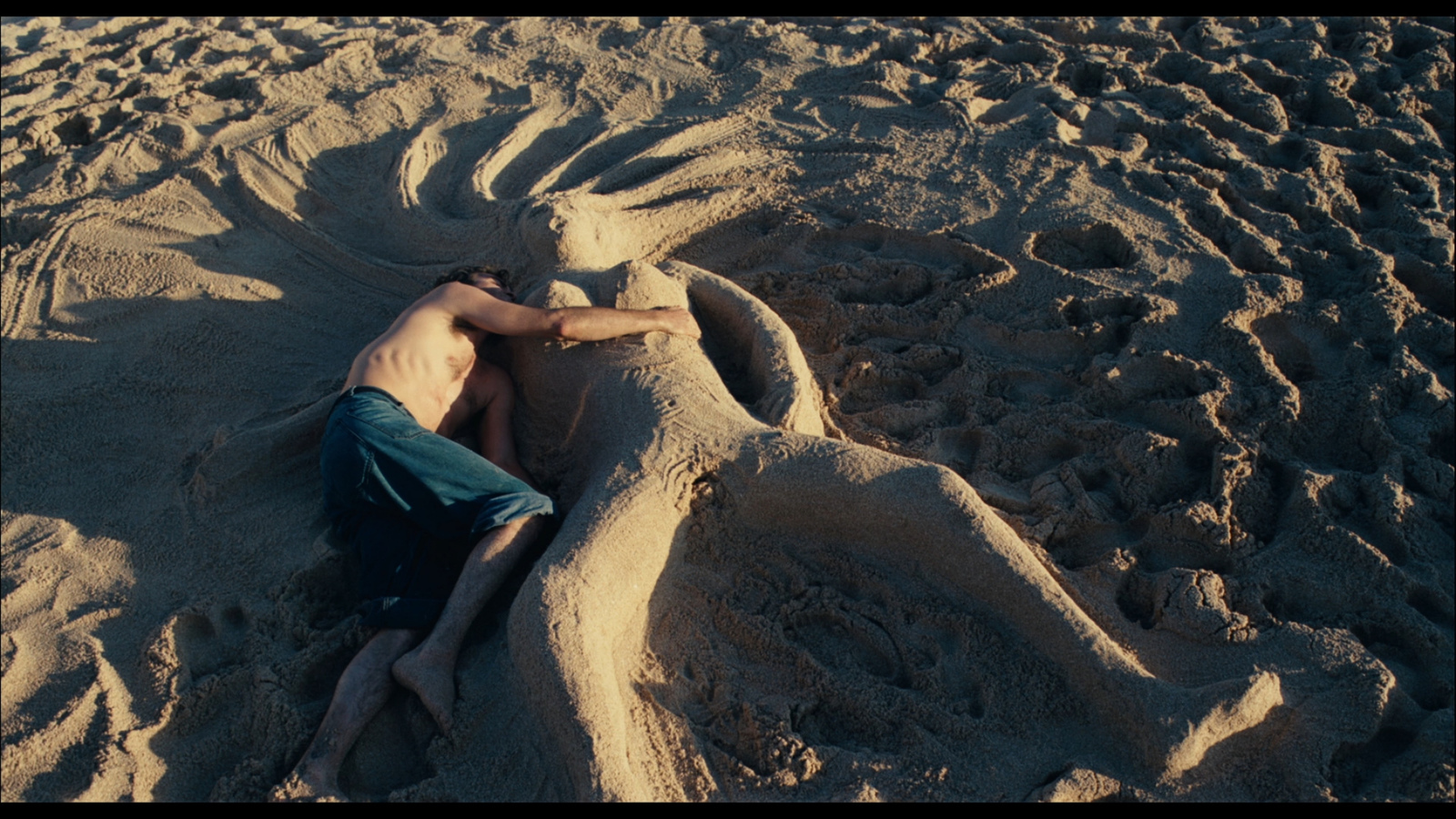 a man laying on top of a sandy beach